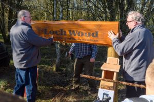 Two men put up the Loch Wood sign